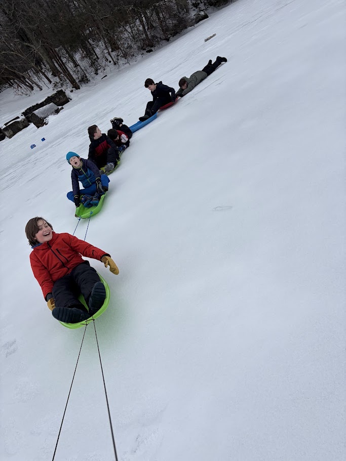 Scouts sledding on a snowy hill.